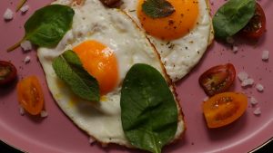 Fried eggs with vegetables on a plate.
